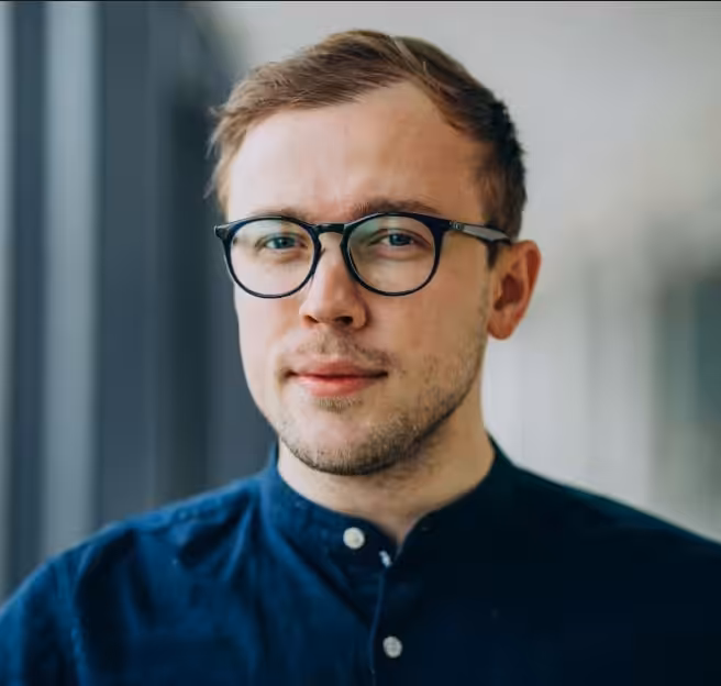 Portrait of Martin Dvorak, a man with short hair, glasses, and a blue shirt, looking directly forward.