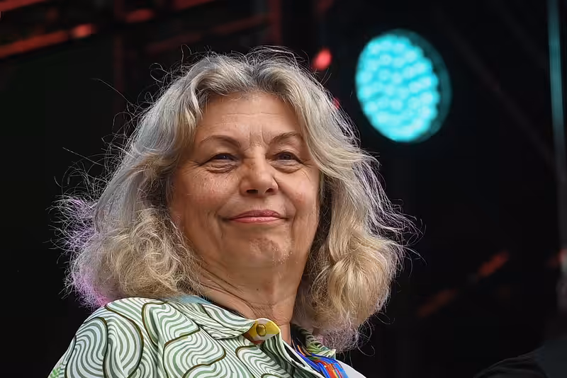 Zlata Holušová smiling gently in front of a bright stage light at an outdoor event.